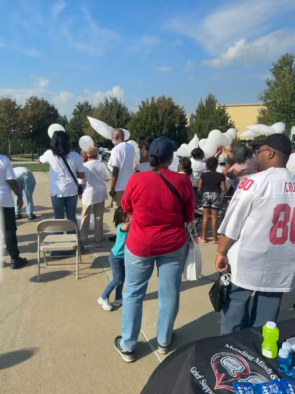 Gathered community with white balloons at the memorial release